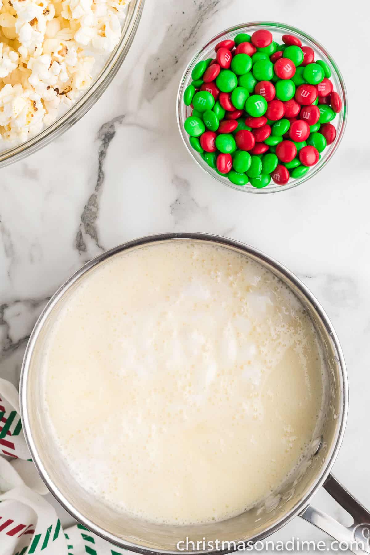 Melted marshmallows and butter in a saucepan with a small bowl of M&Ms on the side