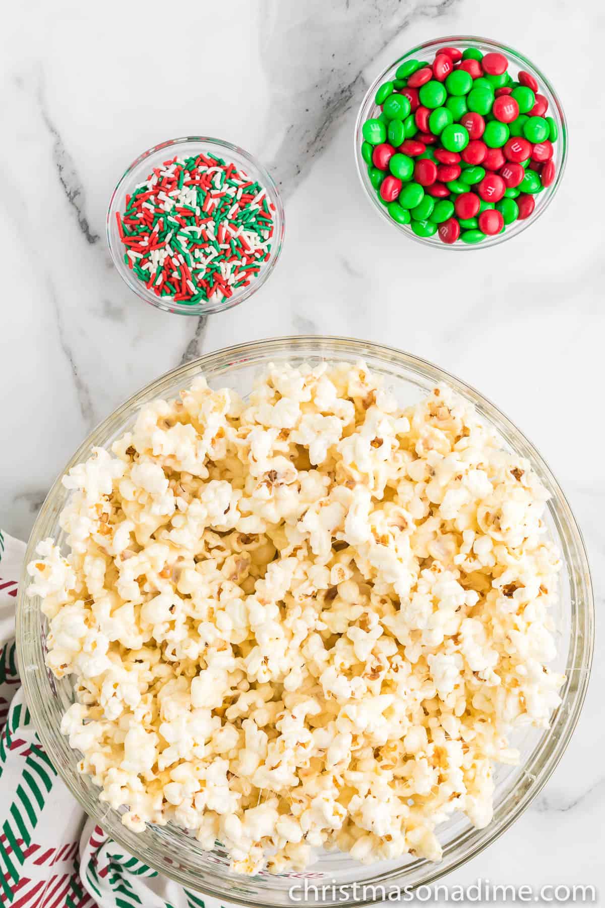 Popcorn in a bowl with a small bowl of sprinkles and M&Ms on the side
