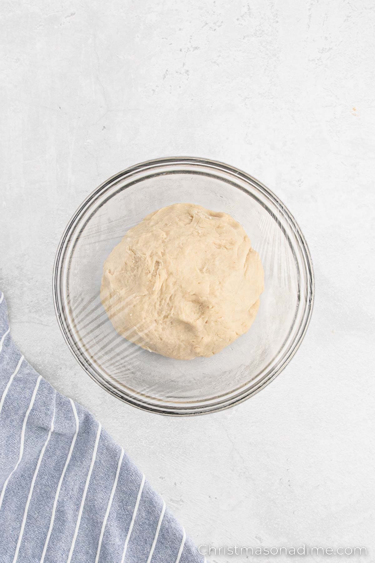 Dough in a bowl covered with plastic wrap