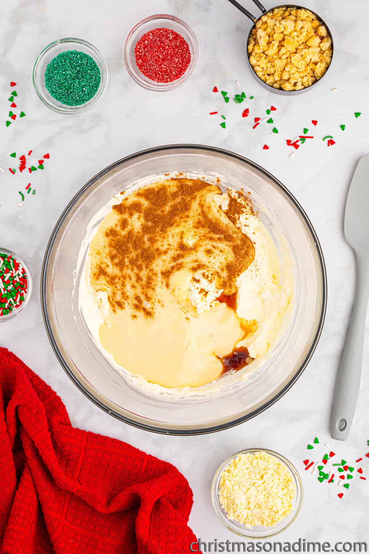 Adding sweetened condensed milk, vanilla and cinnamon with the heavy cream with small bowls of red and green sprinkles on the side