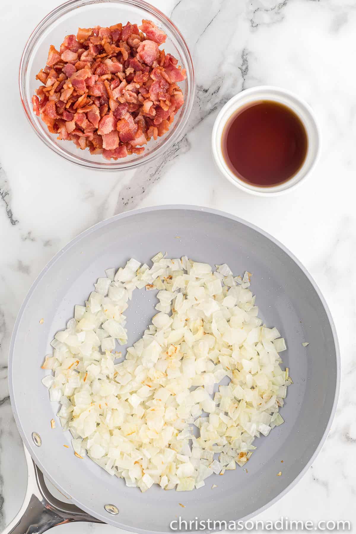 Chopped onions in the skillet with a bowl of chopped cooked bacon on the side