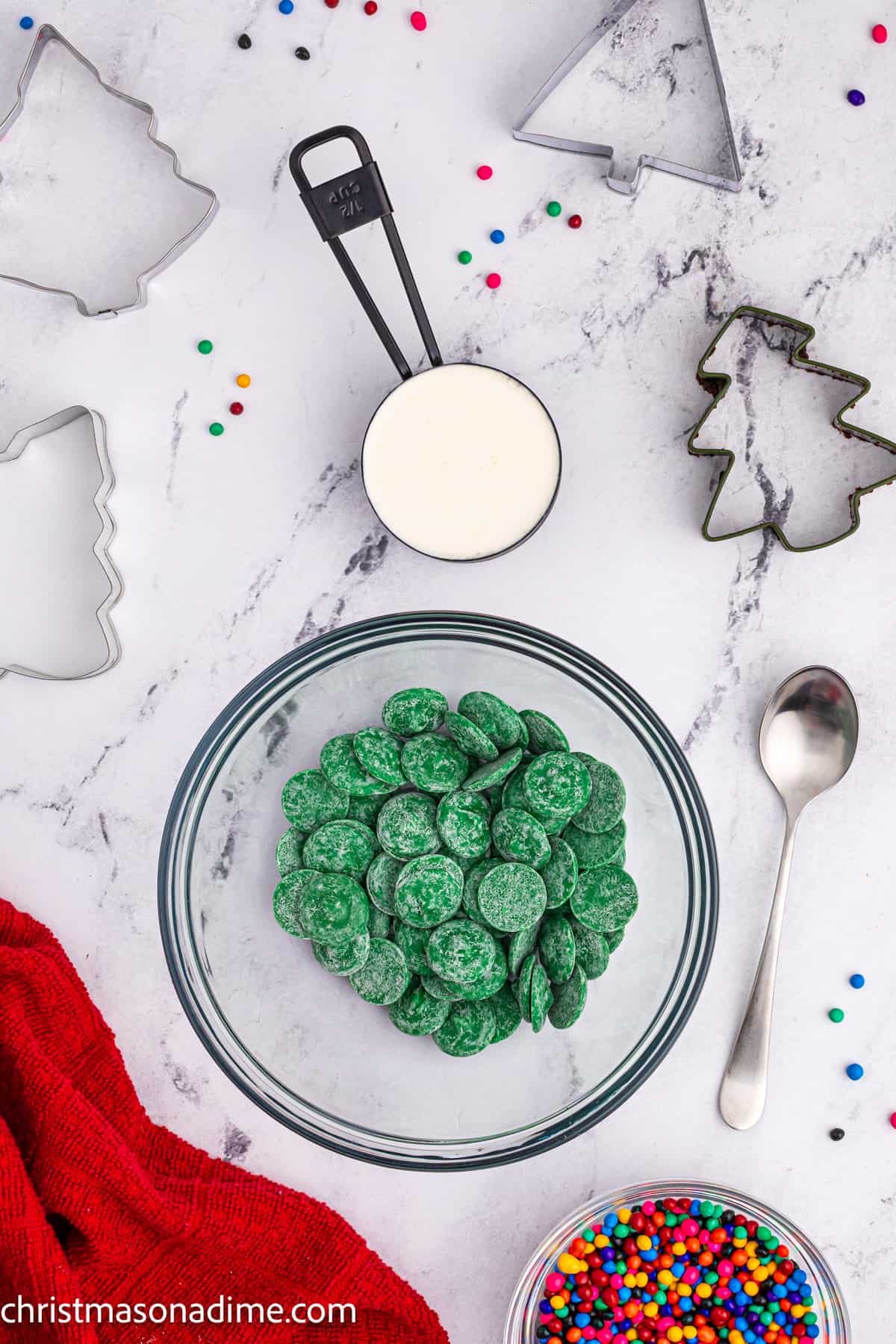 Green Candy Melts in a bowl with a side of heavy cream in a measuring cup